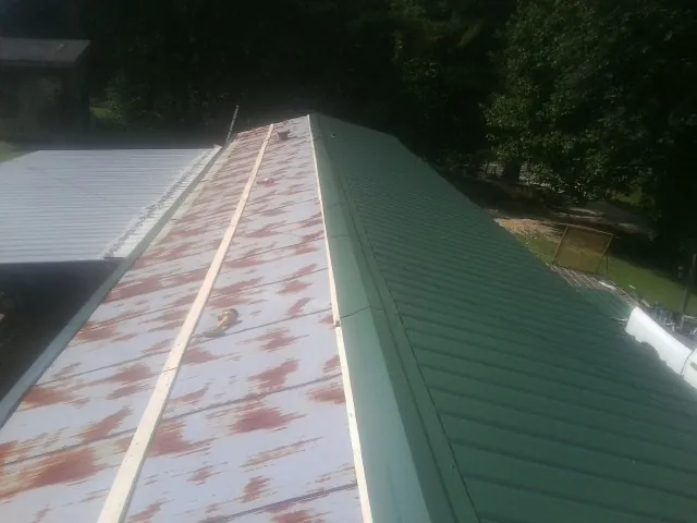 Old rusted panels beside newly installed green metal roofing — Wind Damage Roof Repair by Roofing Brothers in Gardner
