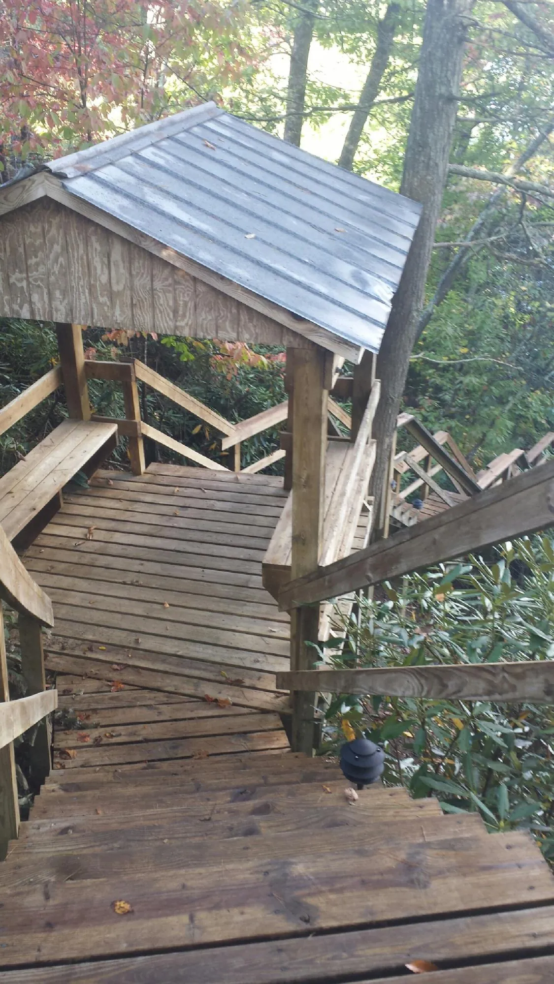 Metal roofed shelter over wooden steps on a wooded walkway — Skylight Repair & Installation work by our crew in Gardner